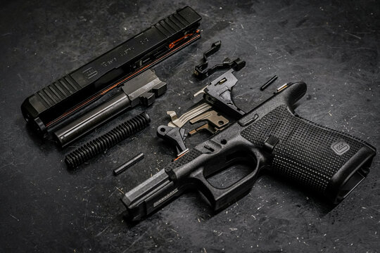 BALTIC STATES - FEBRUARY 17, 2026: Disassembled Glock 19 Generation 6 9mm pistol showing internal components, slide, and barrel on a dark background.
