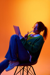 Creative professional sketching ideas on tablet in studio with vibrant gradient lighting. Concept of brainstorming session, concept development and focused digital content creation