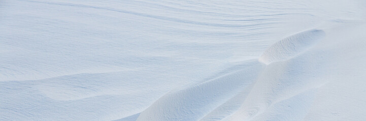 Beautiful winter background with snowy ground. Natural snow texture. Wind sculpted patterns on snow surface. Arctic, Polar region.