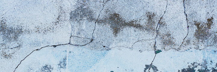 Vintage wall texture. Rough surface of the plastered concrete wall of the building. A pattern with many cracks and old faded peeling paint. Wide panoramic texture for background and design.