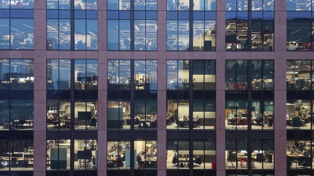 Fragment of the glass facade of a modern corporate building at night. Modern glass office  in city. Big glowing windows.