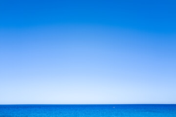 Fototapeta premium A seamless gradient of blue sky meets the tranquil Mediterranean Sea in a minimalist seascape near Cala Goloritze, Baunei, Sardinia. The scene radiates calm and simplicity, with no land or objects