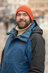 35 year old man standing on city street in winter with pedestrians.