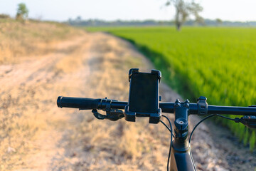 Smartphone Navigation on Bicycle in Countryside Road Travel Concept © patpitchaya