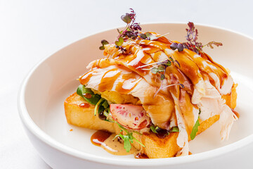 Mouthwatering chicken sandwich atop crispy toast, garnished with fresh herbs and rich sauce