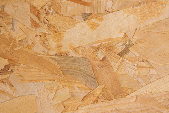 Eco-friendly OSB wood panel texture with recycled wood flakes. Natural chipboard pattern for furniture design, interior, and professional background use.