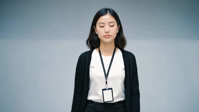European woman in black cardigan and slacks walking confidently toward the camera, showcasing a neutral expression in a minimalistic indoor setting
