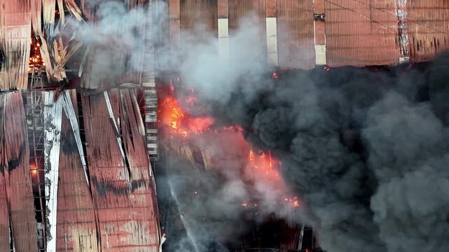 Aerial building is on fire and the smoke is billowing out of it. The fire is so intense that it is visible from a distance