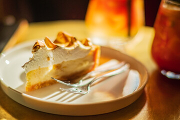 A slice of lemon meringue pie sits beside a cold drink, exuding a cozy vibe
