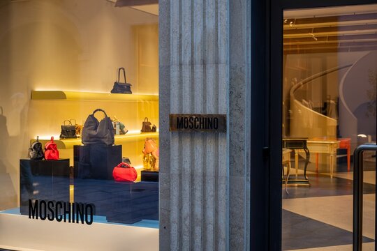 Milan, Italy - 2026, 17 Feb: Moschino SS26 boutique window features luxury handbags and accessories in a stylish, modern display with bold yellow lighting
