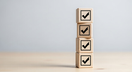 Fototapeta premium Four wooden blocks with checkmarks stacked vertically on a light surface with a plain background, symbolizing confirmation and approval.
