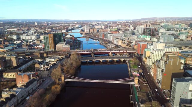Glasgow Bridges over River Clyde, with buildings lining the waterfront. Drone view golden hour with city skyline