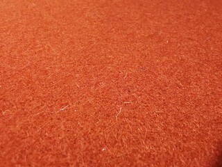 Close-up of a vibrant orange-red textured carpet. The macro view highlights the dense, fuzzy fibers and soft pile, creating a rich abstract background suitable for interior design, upholstery concepts