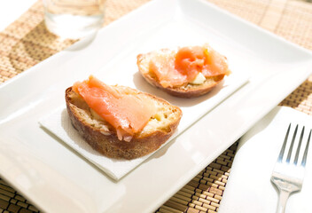 Delicious canapes of salted smoked salmon fillet on a slice of fresh ciabatta on the table