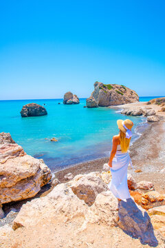 A blonde woman is posing at background Bay of Aphrodite is famous attraction of Cyprus were located between Limassol and Paphos. large stones from ancient times counted as the birthplace of Aphrodite.