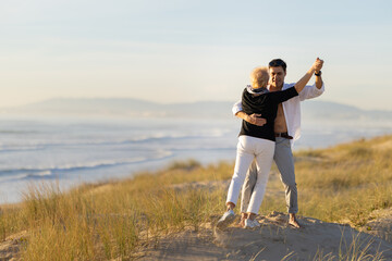 Fototapeta premium Romantic intergenerational couple dancing on beach dune