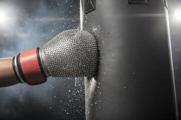 Metallic boxing glove punching black bag with impact particles. 3d render illustration for sport power concepts, fighting competition and heavy strength training