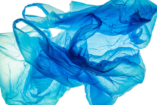 Plastic waste from discarded disposable plastic bags in an aesthetic representation: blue disposable plastic shopping bags crumpled up and thrown away, backlight