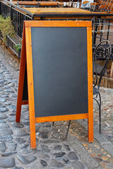 Empty black board panel with wooden frame on city street outside