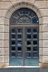 Old vintage closed metal entrance door with arch inside urban area