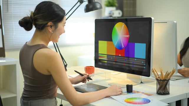 Graphic designer woman working on creative desk computer while using graphic tablet at desk in the office