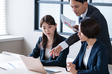  男性が資料を見せながら2人の女性に説明