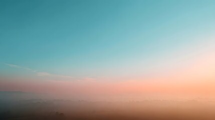 Fototapeta premium Soft pastel hues in the sky meet a misty treed landscape during dawn or dusk creating a serene atmosphere