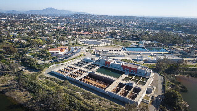 Aerial view of water treatment facility with tanks, buildings, and roadways under a hazy sky, La Mesa, California, United States.