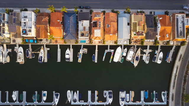 Aerial view of boats nestled in the marina contrasting with the terra cotta roofs of waterfront homes under the fading light., Coronado, California, United States.