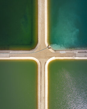 Aerial view of vividly colored water pools partitioned by pale walkways, creating a striking geometric pattern from above, El Centro, California, United States.