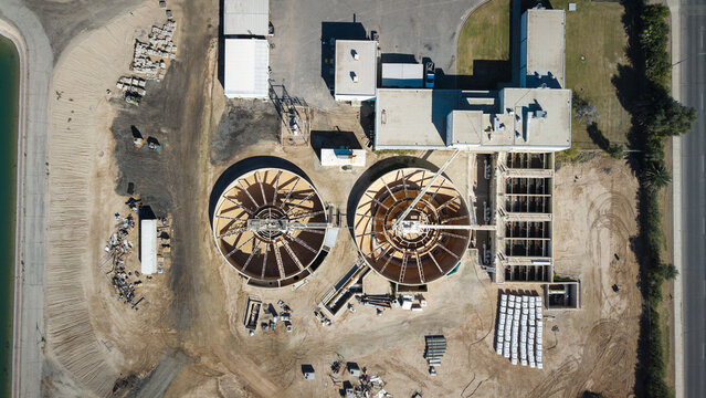 Aerial view of the water treatment plant's circular clarifiers and rectangular settling basins contrasting sharply against the arid landscape, El Centro, California, United States.