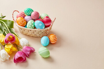 Decorated easter eggs in wicker basket with tulips and copy space