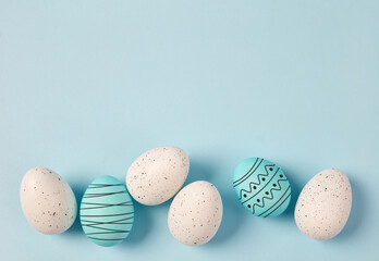 Row of decorated easter eggs on pastel blue background