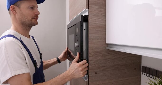 service worker installing integrated microwave oven in the domestic kitchen. household appliance maintenance and repair