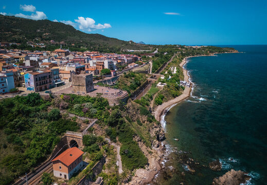 Aerial view of the ancient coastal watchtower stands guard over the rocky shoreline where the blue sea meets the verdant hills, Finale, Sicilia, Italy.