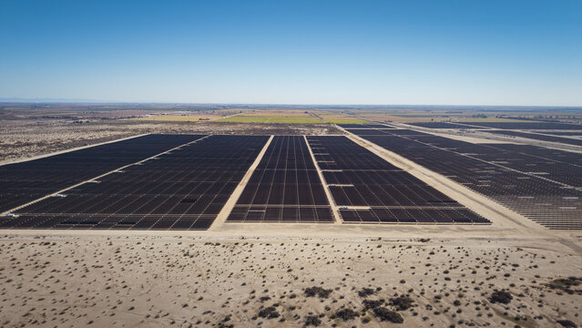 Aerial view of solar panels stretching across the desert landscape, contrasting the arid earth with the promise of clean energy, El Centro, California, United States.