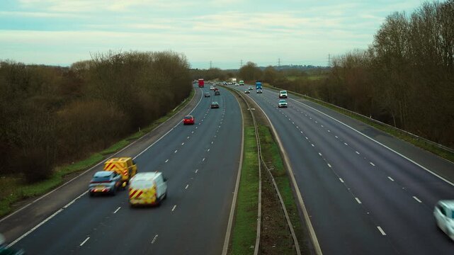 Highway traffic flowing along multi lane motorway with cars and trucks moving in both directions. Supporting transport logistics, enabling fast cargo delivery and commuter travel. Representing busy