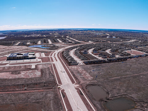 Aerial view of the geometric precision of suburban homes meeting the wild expanse of open fields under a vast sky, Little Elm, Texas, United States.