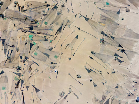 Aerial view of fishing nets spread across the sandy expanse, creating a textured pattern from above, Cox's Bazar, Chittagong Division, Bangladesh.