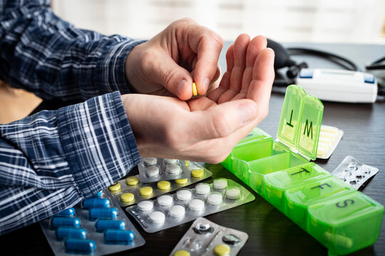 Middle aged caucasian man counts out pills for distributing scheduled dose of medication into pillbox