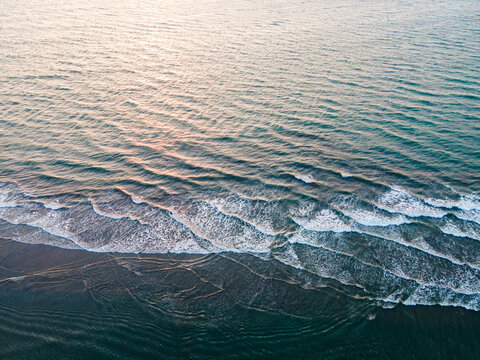 Aerial view of the sea meeting the shore, the waves creating a white lace pattern against the dark sand, Cox's Bazar, Chittagong Division, Bangladesh.