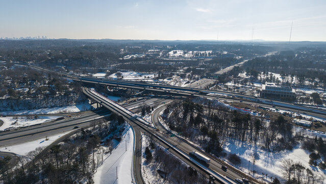 Aerial view of the intricate highway interchange weaving through a landscape of snow-dusted trees under a clear sky, Massachusetts, Massachusetts, United States.