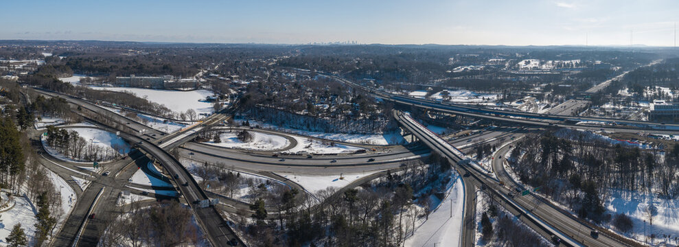 Aerial view of a complex interchange in winter, where snow-covered landscapes meet the stark gray of the highways, Massachusetts, United States.