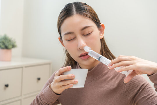 Health care wash nose, cleaning nose concept. Nasal irrigation asian young woman illness have a flu, fever, have a runny nose. Girl washes out nose with syringe and saline, infection, dust allergic.