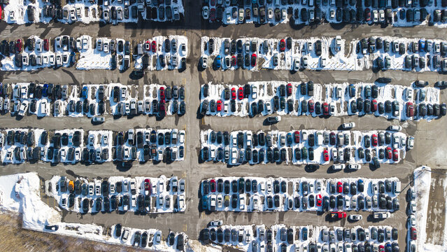 Aerial view of a vast parking lot filled with cars, dusted with snow, creating a stark contrast of white against the dark asphalt, Framingham, Massachusetts, United States.