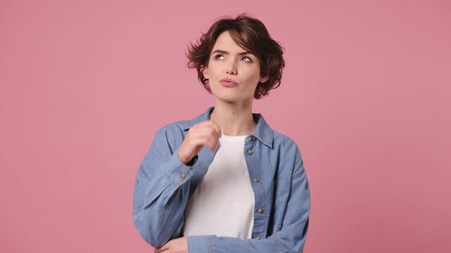 Young pensive smart woman wears blue shirt white t-shirt casual clothes look around think scratches at temple comes up with idea raised finger get plan isolated on plain pastel light pink background