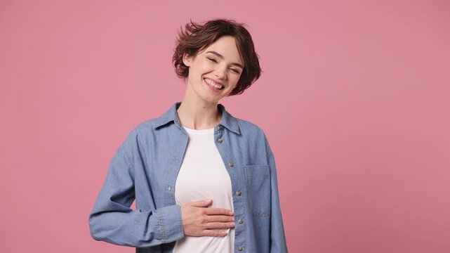 Young smiling happy satisfied woman she wearing blue shirt white t-shirt casual clothes stroking belly show thumb up isolated on plain pastel light pink background studio portrait. Lifestyle concept