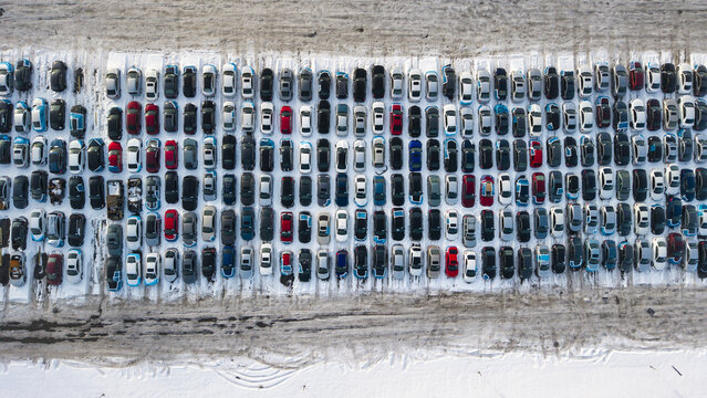 Aerial view of neatly arranged cars in a snow-dusted parking lot create a grid of color and form, offering a stark contrast to the winter landscape, Fall River, Massachusetts, United States.