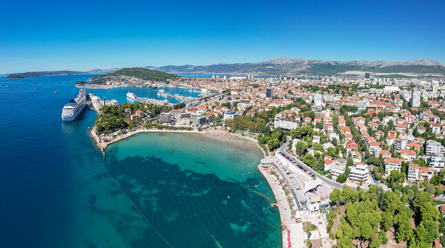 Aerial view of the vibrant, turquoise waters of Bacvice Beach meeting the bustling city, Split, Dalmatian Coast, Croatia.