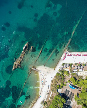 Aerial view of crystal-clear turquoise waters meeting the rugged coastline at Ovcice Beach, Split, Dalmatian Coast, Croatia.